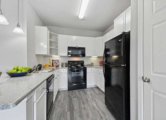 A black refrigerator is in a white kitchen.
