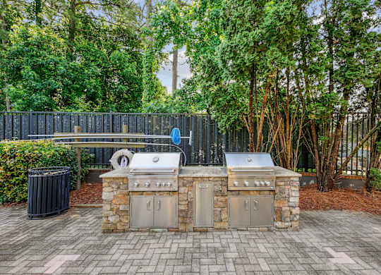 A stone and metal outdoor kitchen with a grill and sink.