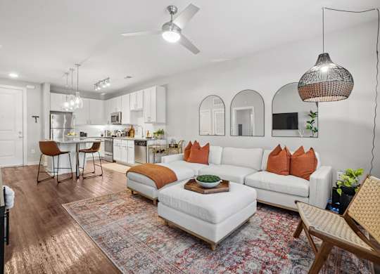 A modern living room with a white sofa and orange pillows.
