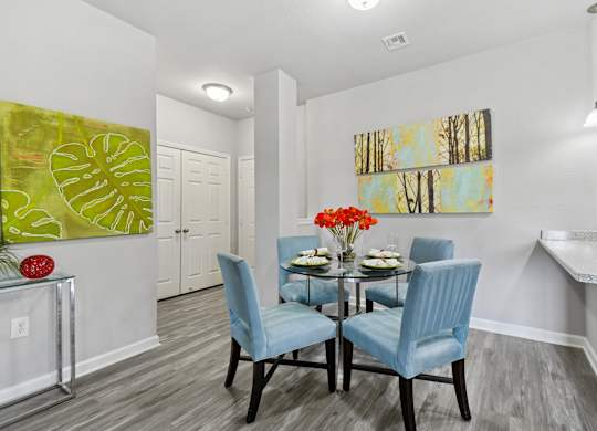 A dining room with a table set for two and a painting on the wall.