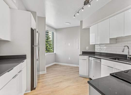 an empty kitchen with white cabinets and black counter tops