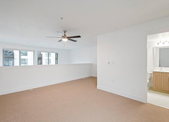 Carpeted loft area with ceiling fan and ensuite bathroom at Six Oaks Apartments, Bothell