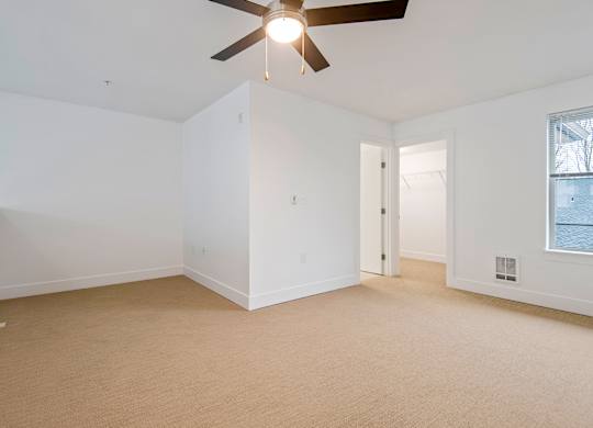 Empty carpeted bedroom with vaulted ceiling and ceiling fan at Six Oaks Apartments, Washington