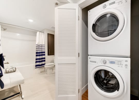 a white washer and dryer in a bathroom with a toilet and a shower