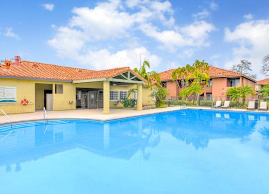 A swimming pool in front of a building with a red roof.
