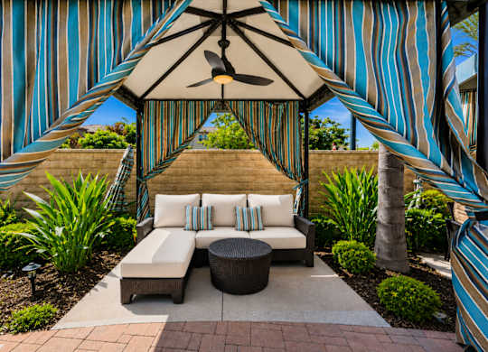 A patio with a striped awning and a white couch.