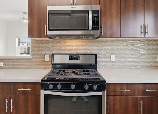 A modern kitchen with a stove and microwave above it.
