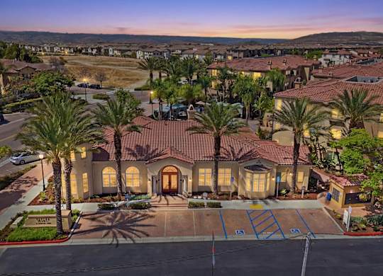A large house with a driveway and palm trees in front.