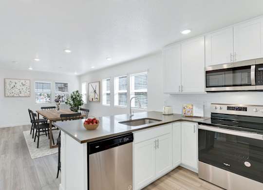 a kitchen with white cabinets and stainless steel appliances and a dining room table