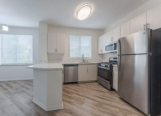 A modern kitchen with stainless steel appliances and wooden flooring.