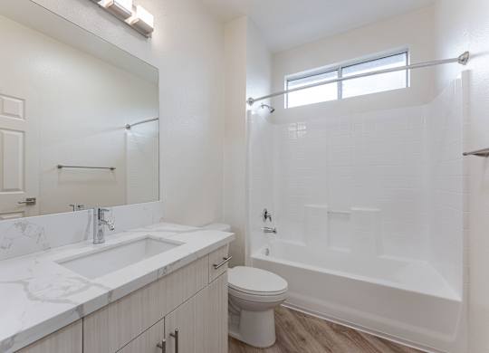 A white bathroom with a toilet, sink, and bathtub.