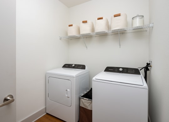 a small laundry room with a washer and dryer and a shelf with white
