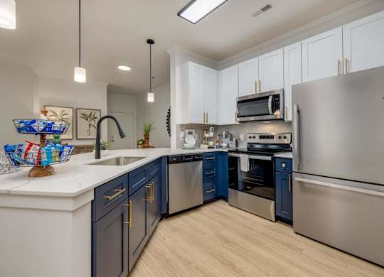 A modern kitchen with a stainless steel refrigerator and dark blue cabinets.