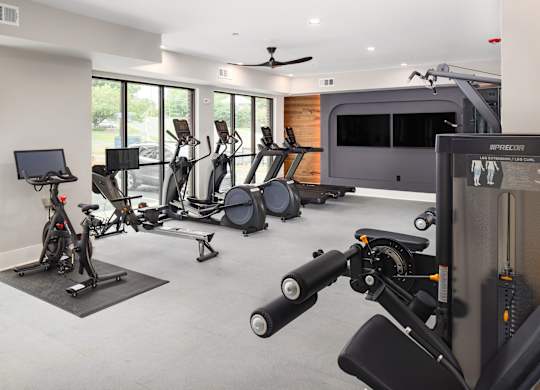 a gym with various exercise equipment and a tv in the corner