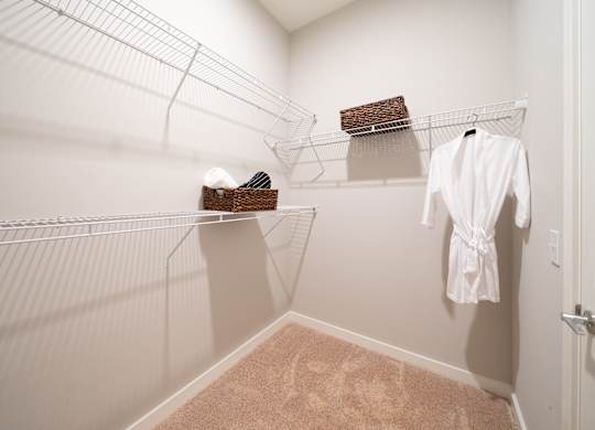 a spacious walk in closet with a white robe and hanging racks