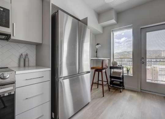 a kitchen with a refrigerator and a door to a balcony