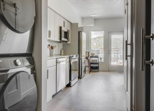 a kitchen with a washer and dryer and a door to a living room