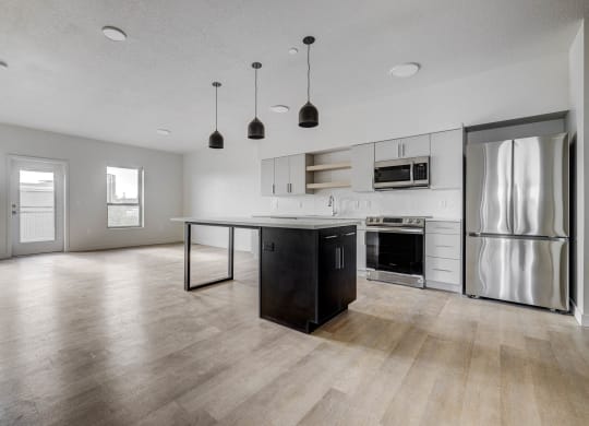 an empty kitchen and living room with stainless steel appliances and a island