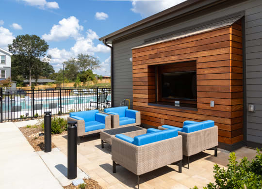 a patio with couches and a tv on the side of a house