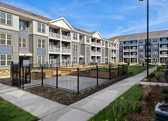 A row of modern apartment buildings with a black fence in front.