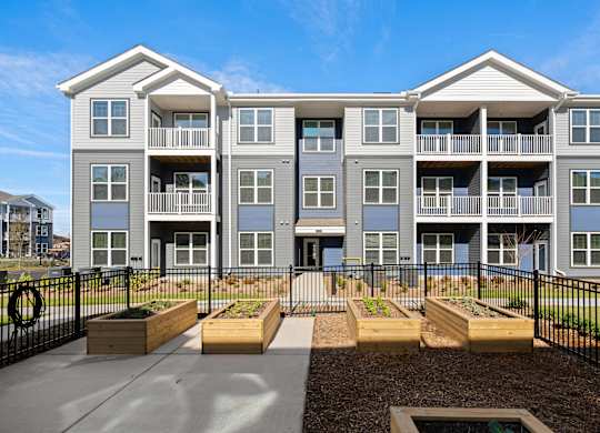 Apartment complex with a black fence and planters in front.