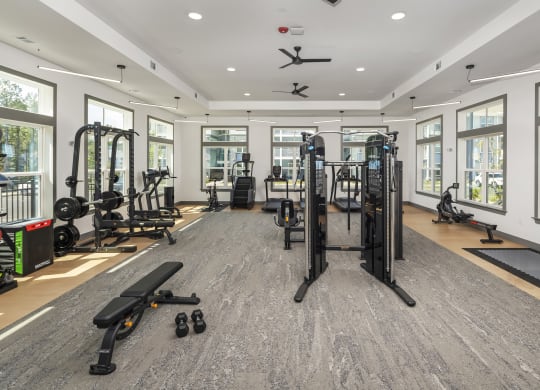 a gym with weights and cardio equipment in a building with windows