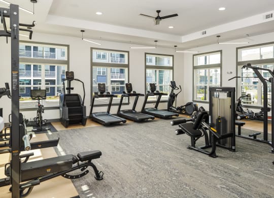 a gym with treadmills and other exercise equipment in a building with windows