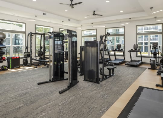 a gym with weights and cardio equipment in a building with windows