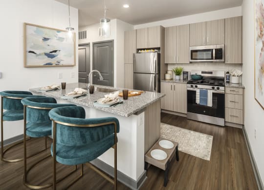 a kitchen with a marble counter top and a island with three chairs