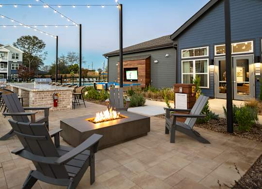 A patio with a fire pit and chairs.