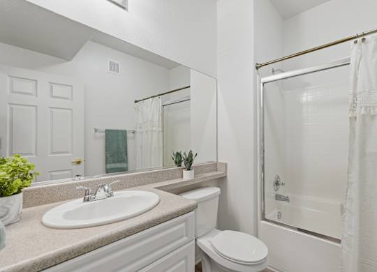 A white bathroom with a sink, toilet, and shower.