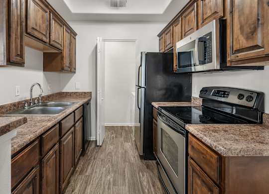 A kitchen with dark wood cabinets and a black refrigerator.