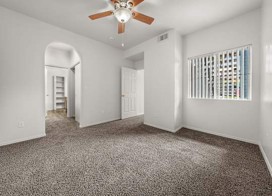 A spacious room with a ceiling fan and carpeted floor.