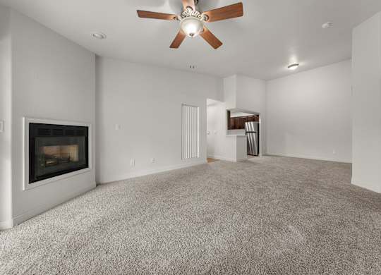 A spacious living room with a fireplace and a ceiling fan.
