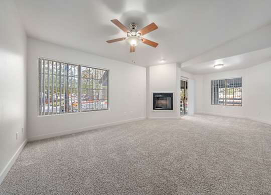 A spacious living room with a fireplace and a ceiling fan.