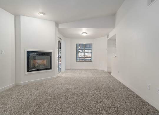 A spacious living room with a fireplace and a window.