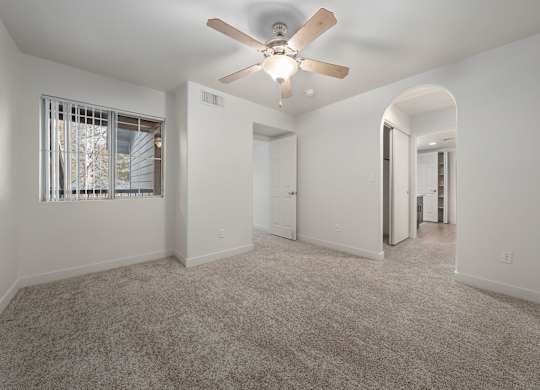 A spacious room with a ceiling fan and carpeted floor.