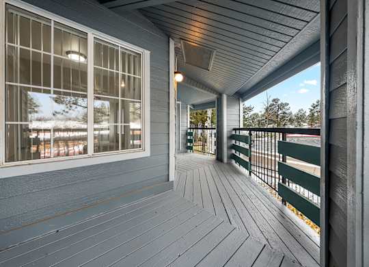 A porch with a grey floor and a green railing.