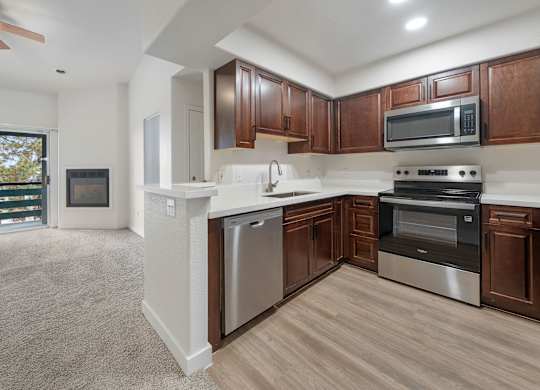 A modern kitchen with dark wood cabinets and stainless steel appliances.
