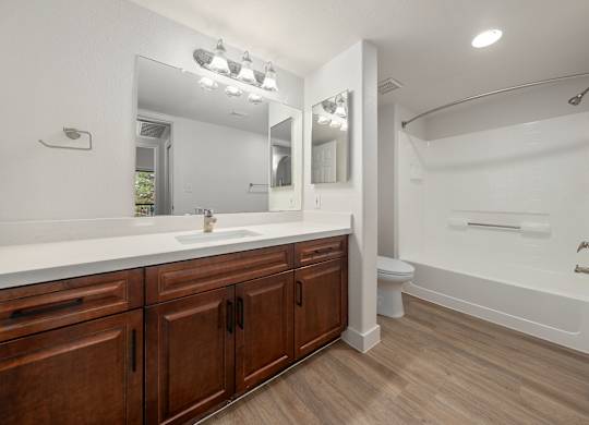 A bathroom with a white countertop and wooden cabinets.