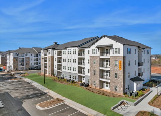 an image of an apartment building with green grass and a parking lot