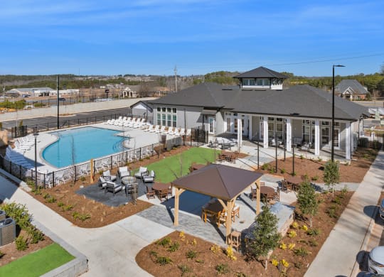 an aerial view of a resort style pool and clubhouse with tables and chairs