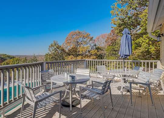 A wooden deck with a table and chairs overlooking a pool.