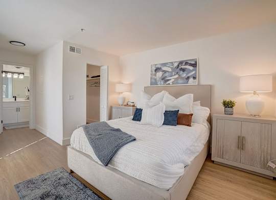 A bedroom with a large bed and a painting above it.