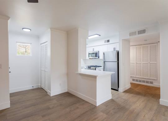 A kitchen with white cabinets and a refrigerator.