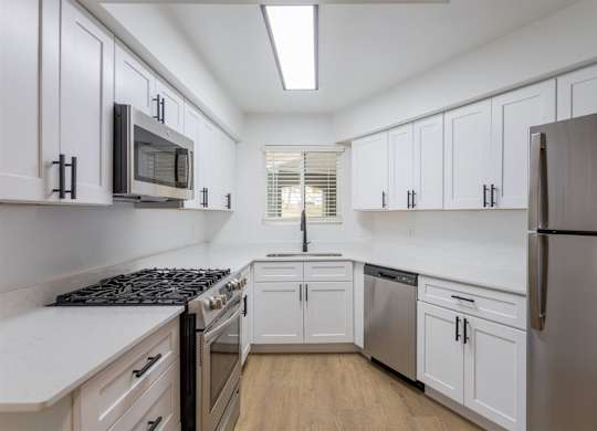 A kitchen with white cabinets and a black stove top oven.