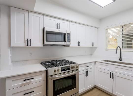 A kitchen with white cabinets and a stove top oven.