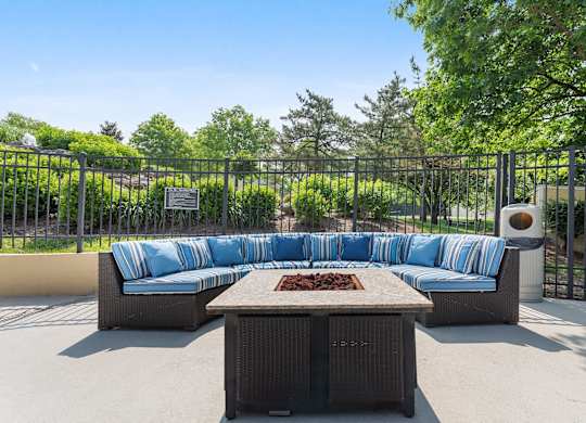 A patio with a sofa and a table with a plaque on the fence.