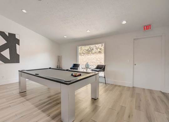 A pool table in a room with a chair and a painting.