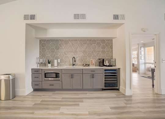 A modern kitchen with a grey backsplash and a trash can.